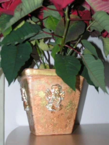Stari cvetlični lonec okrašen z odlitki angelčkov in zlatimi lističi.